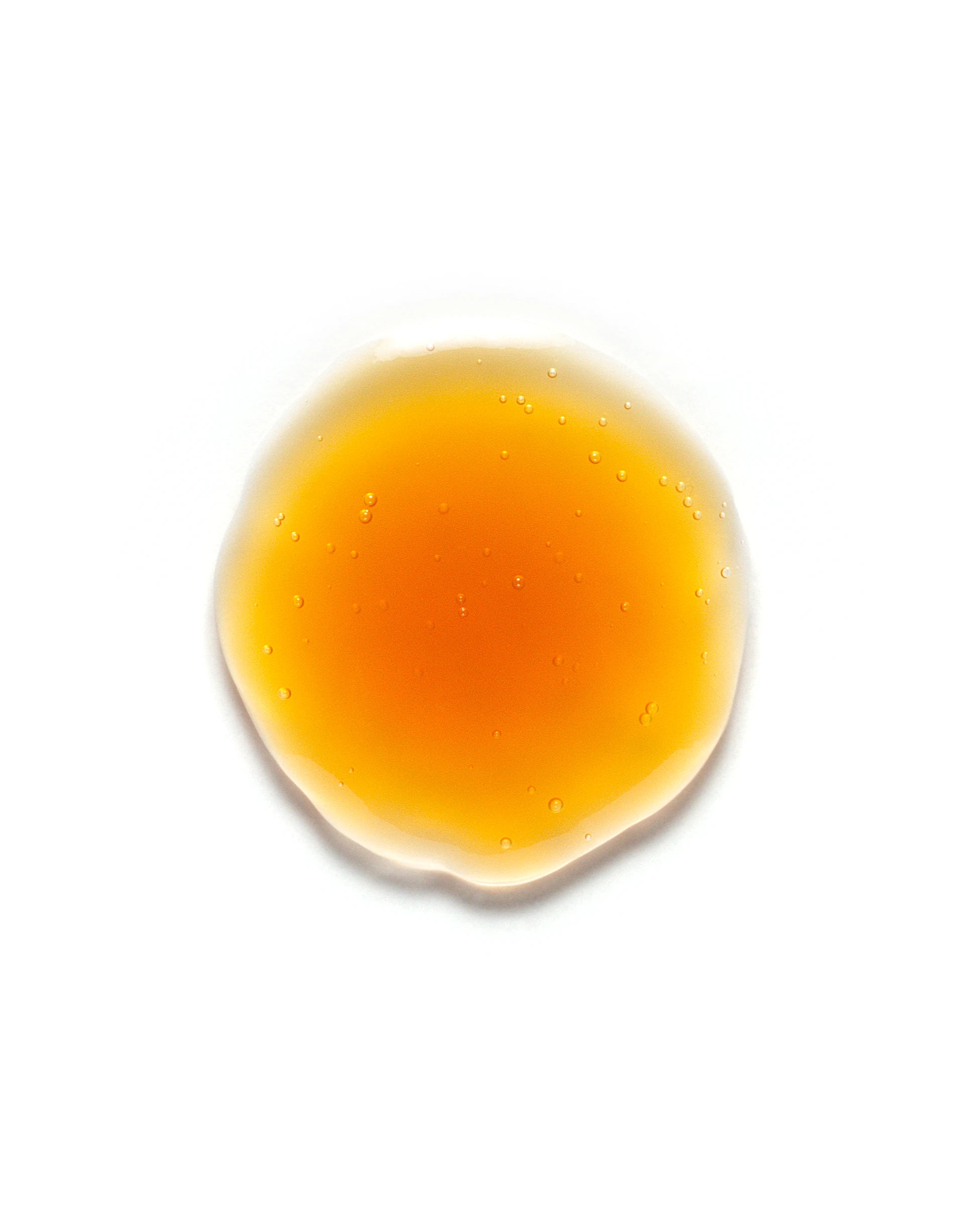 Amber-toned droplet of Cucumber Refreshing Eye Serum on a white background. The lightweight, gel-like texture with visible microbubbles highlights its cooling, de-puffing properties for under-eye care. Skincare product designed to hydrate and revitalize tired eyes.